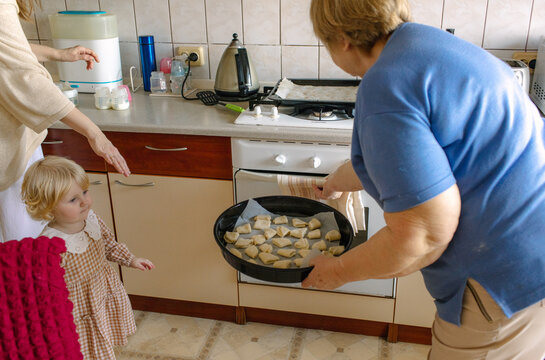 
elderly woman putting baked goods in the oven