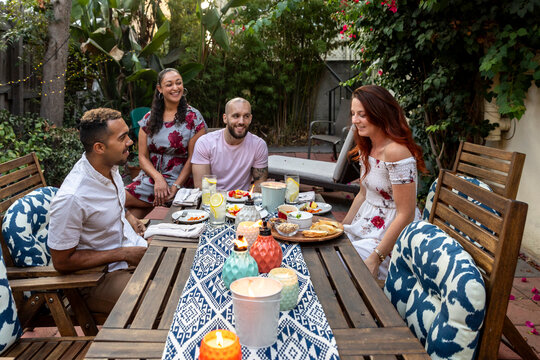 Friends Enjoying a Cozy Evening Meal in a Beautiful Backyard Set