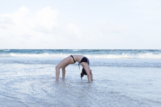 Young woman practising yoga on the beach