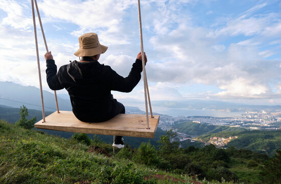 Asian man swinging on a swing in high altitude mountains