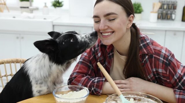 Woman making cookies near cute dog at wooden table in kitchen
