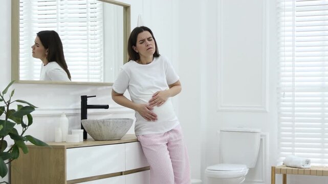 Pregnant woman suffering from nausea over sink in bathroom. Toxicosis during pregnancy