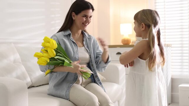 Happy Mother's Day. Little girl greeting her mom with bouquet of beautiful tulips at home. Camera moving forward