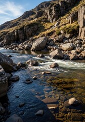 Rugged mountain slope with a clear fast flowing river cascading over rocks and boulders under a bright blue sky with wispy clouds showcasing natural beauty and wilderness