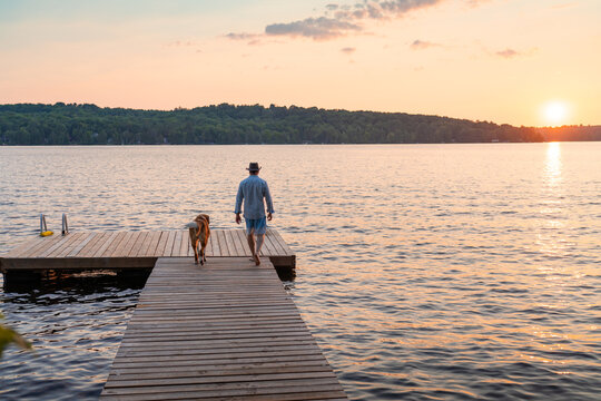 Man and Dog Walking on Cottage Dock at Sunset