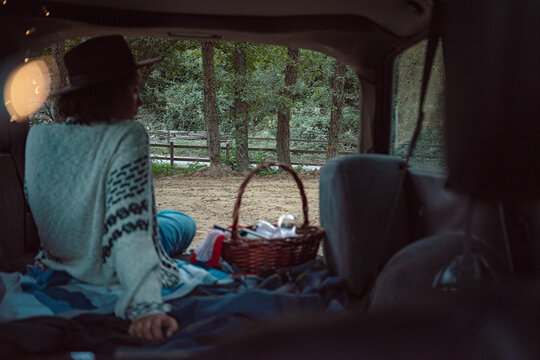 Young woman sitting on the luggage carrier of a blue classic car