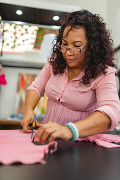 Seamstress cutting pink fabric
