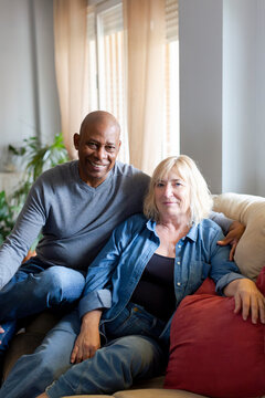 Happy diverse senior couple posing at home living room