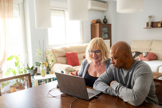 Senior couple at home living room checking data on laptop 