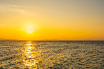 Obraz premium Nature sky breathtaking golden sunset over a calm ocean, with the entire sky and water bathed in brilliant shades of yellow and orange. Streaky clouds enhance the dramatic display of light 