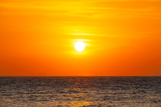 Nature sky breathtaking golden sunset over a calm ocean, with the entire sky and water bathed in brilliant shades of yellow and orange. Streaky clouds enhance the dramatic display of light	

