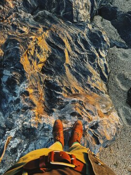 Feet Standing on Textured Rock at Sunset