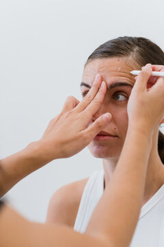 Beautician applying cream on woman's forehead for aesthetic treatment