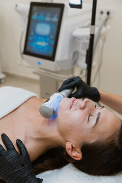 Beautician performing led light therapy treatment on woman's neck