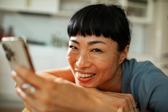 Smiling woman video chatting on smartphone at home