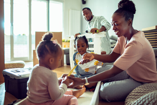 Family with kids assembling furniture in new home