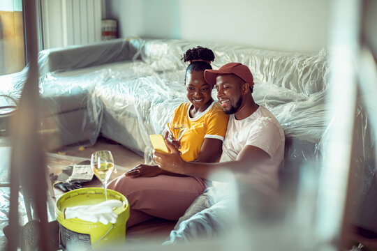 Happy couple taking selfie during home painting in living room