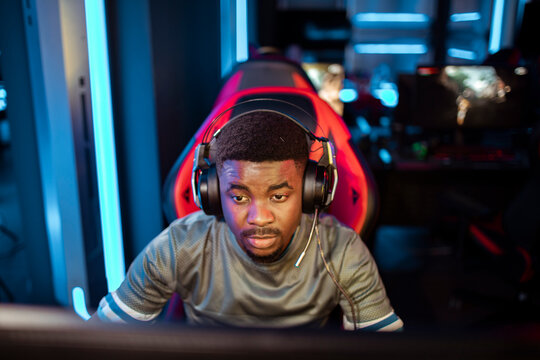 Focused young man gaming with headset at esports center