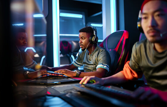 Esports teammates gaming at computers in neon arena