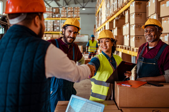 Supervisor and warehouse workers shaking hands in distribution center