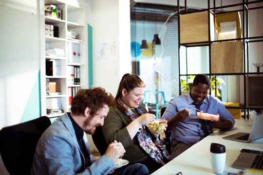 Coworkers eating lunch together in modern office
