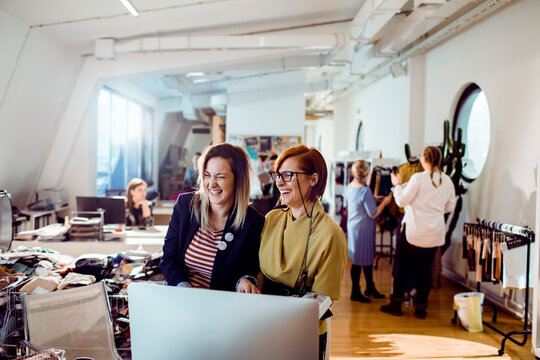 Fashion designers collaborating at computer in creative studio office