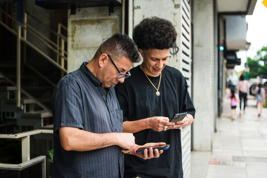 Father and adult son using their phones