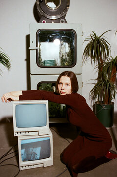 Young woman poses with vintage televisions