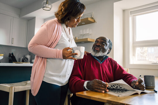 Multiracial Senior Couple Enjoying Morning Coffee and Crosswords