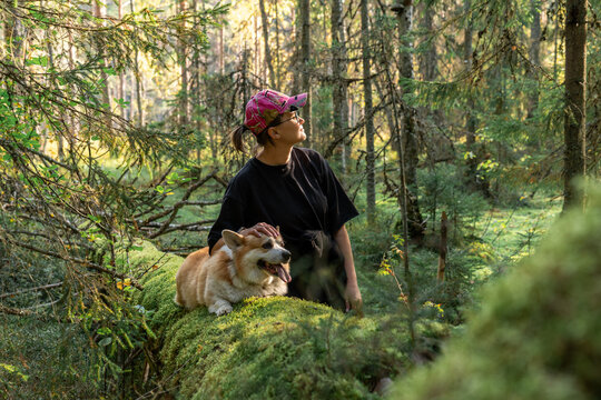 Woman and Dog on Mossy Log in Forest
