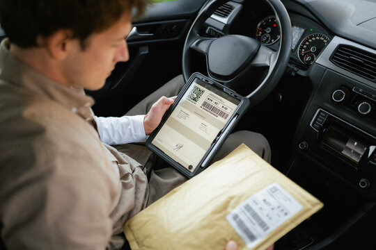 The postman uses a tablet sitting in the car