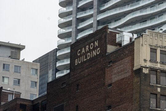 MONTREAL, CANADA, 23 December 2025 : Historic urban architecture, Caron Building, modern skyscraper, cityscape, architectural contrast