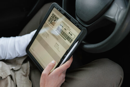 The postman uses a tablet sitting in the car