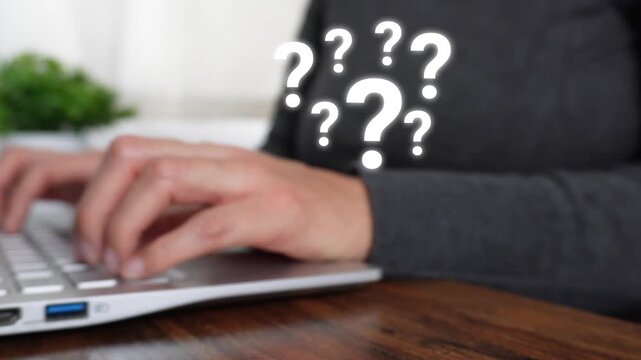 Close-up of a woman's hand working on a computer as she points to an animation of several question marks.