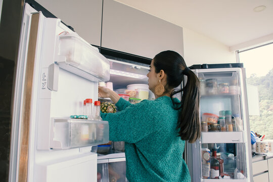 Latin woman looking inside the refrigerator