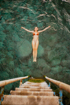 Woman swimming in the sea beside the ladder 