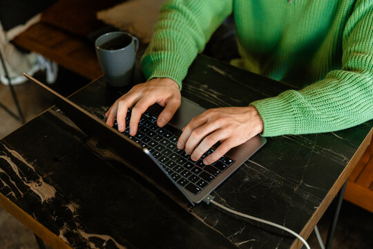 Man's hands typing on a laptop
