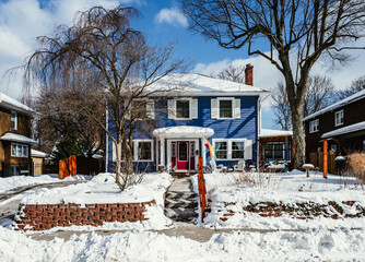 Naklejka premium A blue house in snow on a sunny day after a winter storm