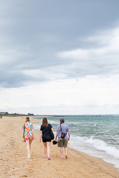 Friends walks the beach contemplating under vast sky in Melbourne