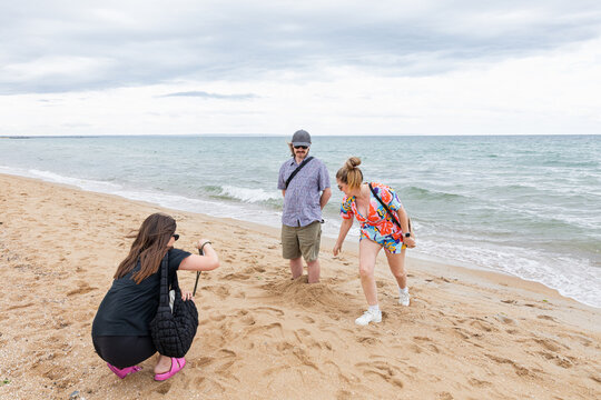 Three people interacting on the sandy beach in Melbourne Australia
