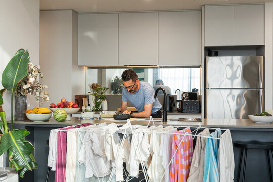 Man cooking in modern kitchen with drying laundry rack