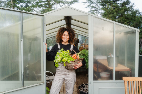 Smiling Woman Holding A Basket Of Organic Vegetables In A Storage Room