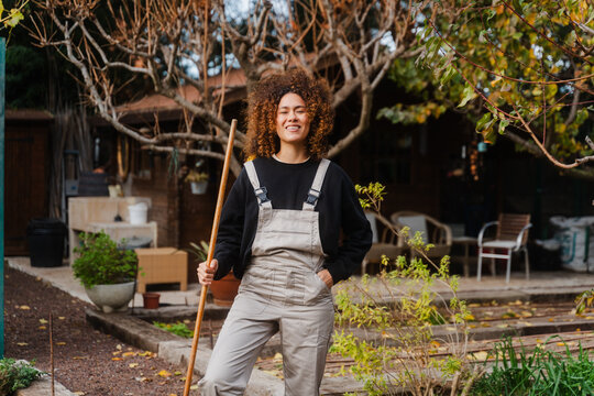 Smiling Woman With Rake In Farm At Greenhouse