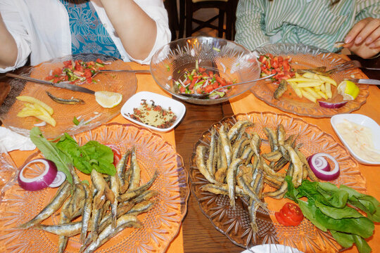 two women are sitting at a table and eating fried fish