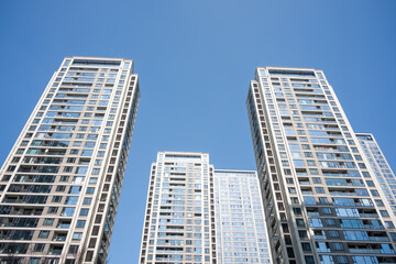 Obraz premium Modern high-rise residential buildings captured from a low angle against a clear blue sky