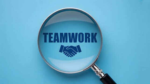 Close up view of a magnifying glass emphasizing the word TEAMWORK with a handshake symbol on a bright blue sur