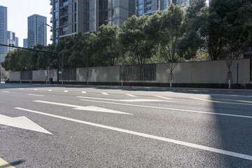 Urban road with green trees, high-rise buildings, and construction barriers under clear daylight © zhu difeng