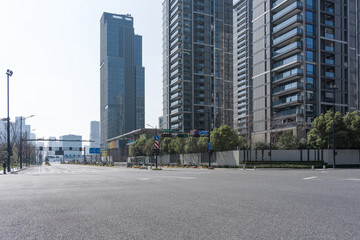 Empty urban street with towering modern skyscrapers and clean asphalt road under clear daylight