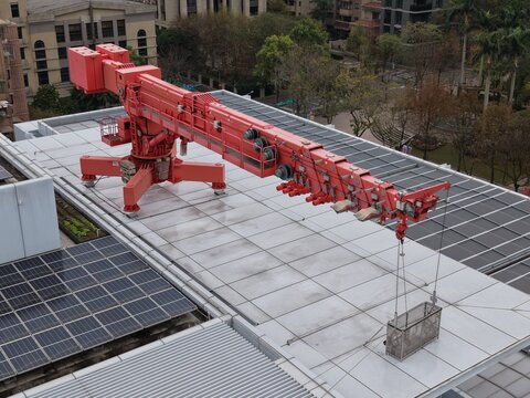 A red building maintenance unit BMU crane on a skyscraper roof.