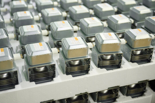 Magnetrons arranged in rows for efficient microwave oven production setup at manufacturing facility